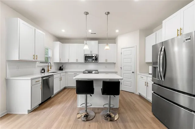 a kitchen with kitchen island a refrigerator a stove a sink and a chairs