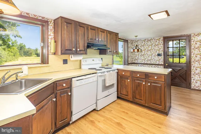 a kitchen with a sink cabinets wooden floor and a window