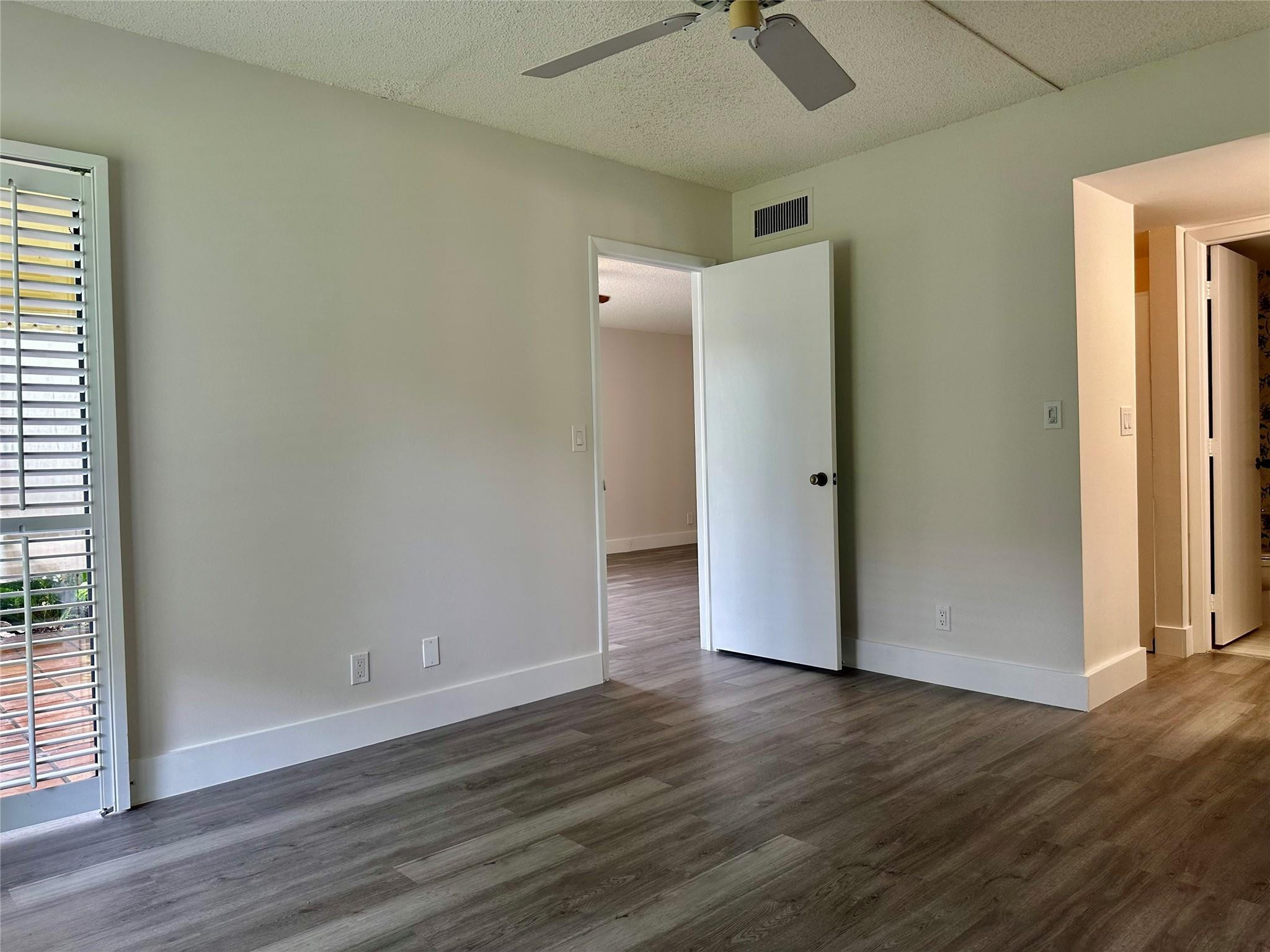 159 Northwest 70th Street, Unit 517 Boca Raton, FL 33487 - Photo 18 of 30 an empty room with wooden floor and a ceiling fan
