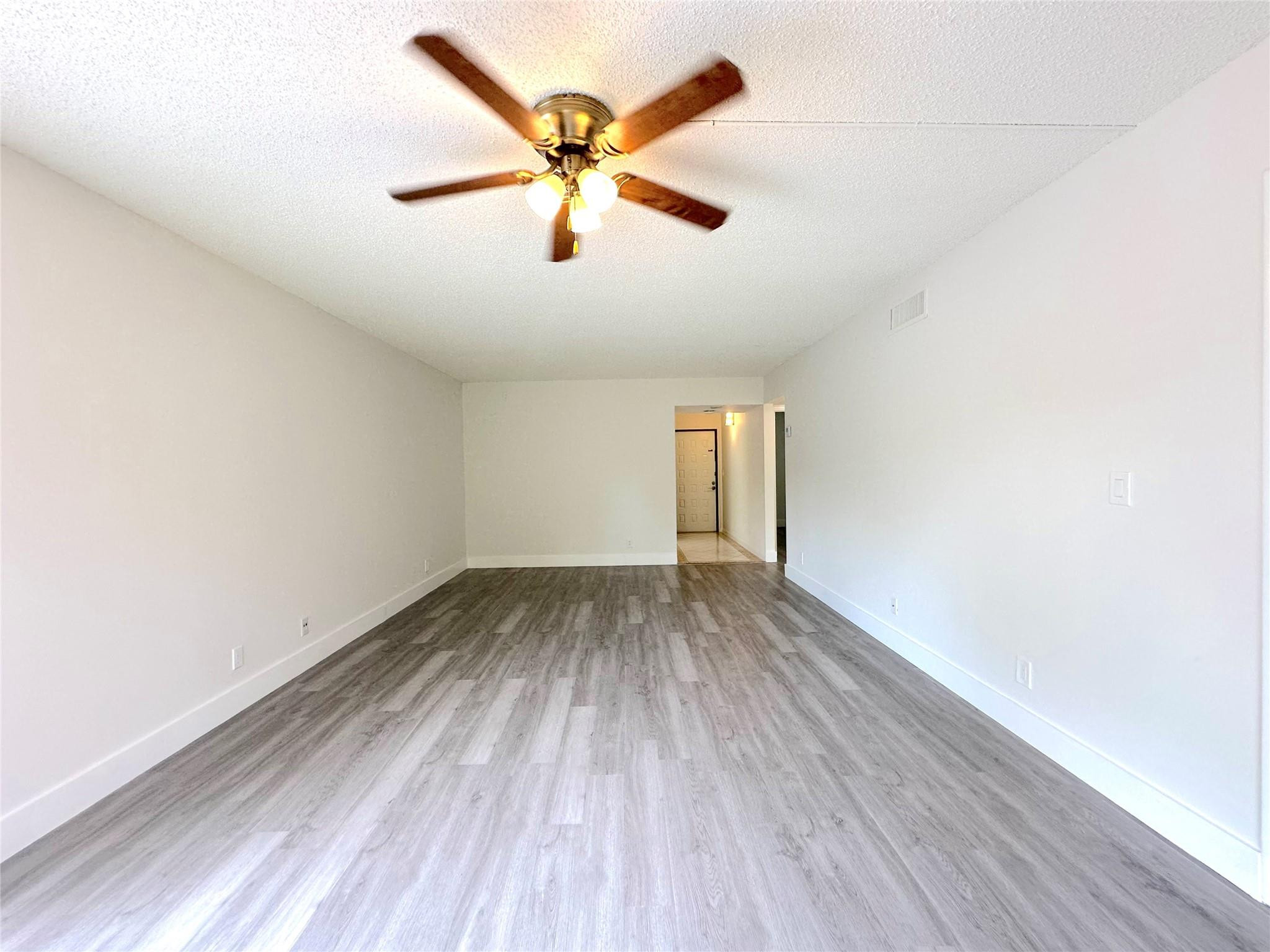 159 Northwest 70th Street, Unit 517 Boca Raton, FL 33487 - Photo 9 of 30 an empty room with wooden floor and windows