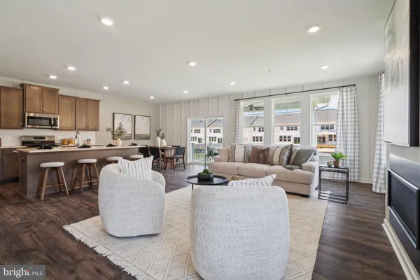 a living room with couches and kitchen view with wooden floor