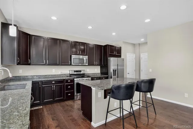 a kitchen with stainless steel appliances granite countertop a stove top oven a sink dishwasher a dining table and chairs