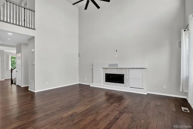 an empty room with wooden floor fireplace and windows
