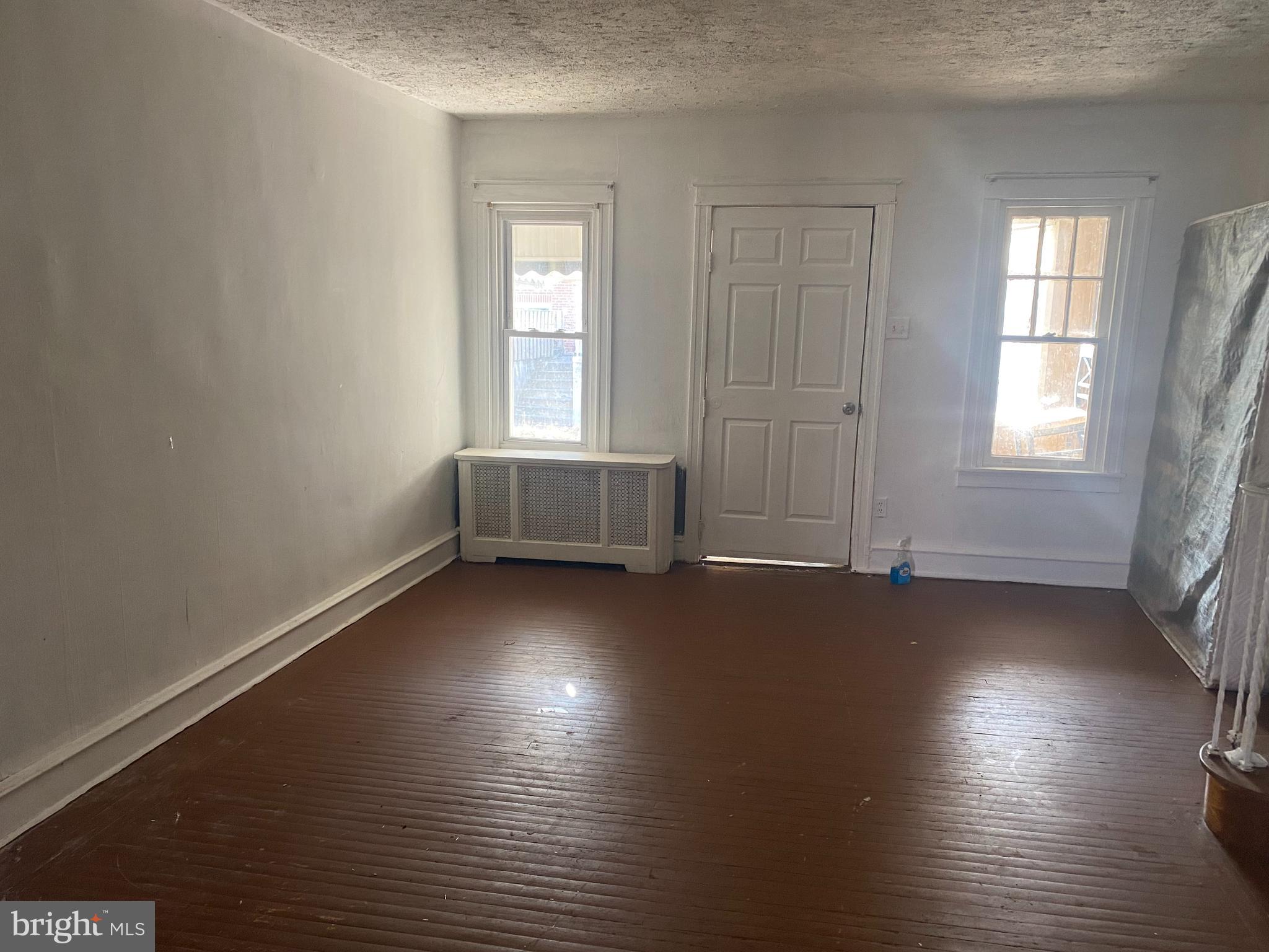 89 Lamport Road Upper Darby, PA 19082 - Photo 3 of 22 an empty room with wooden floor and windows with curtains