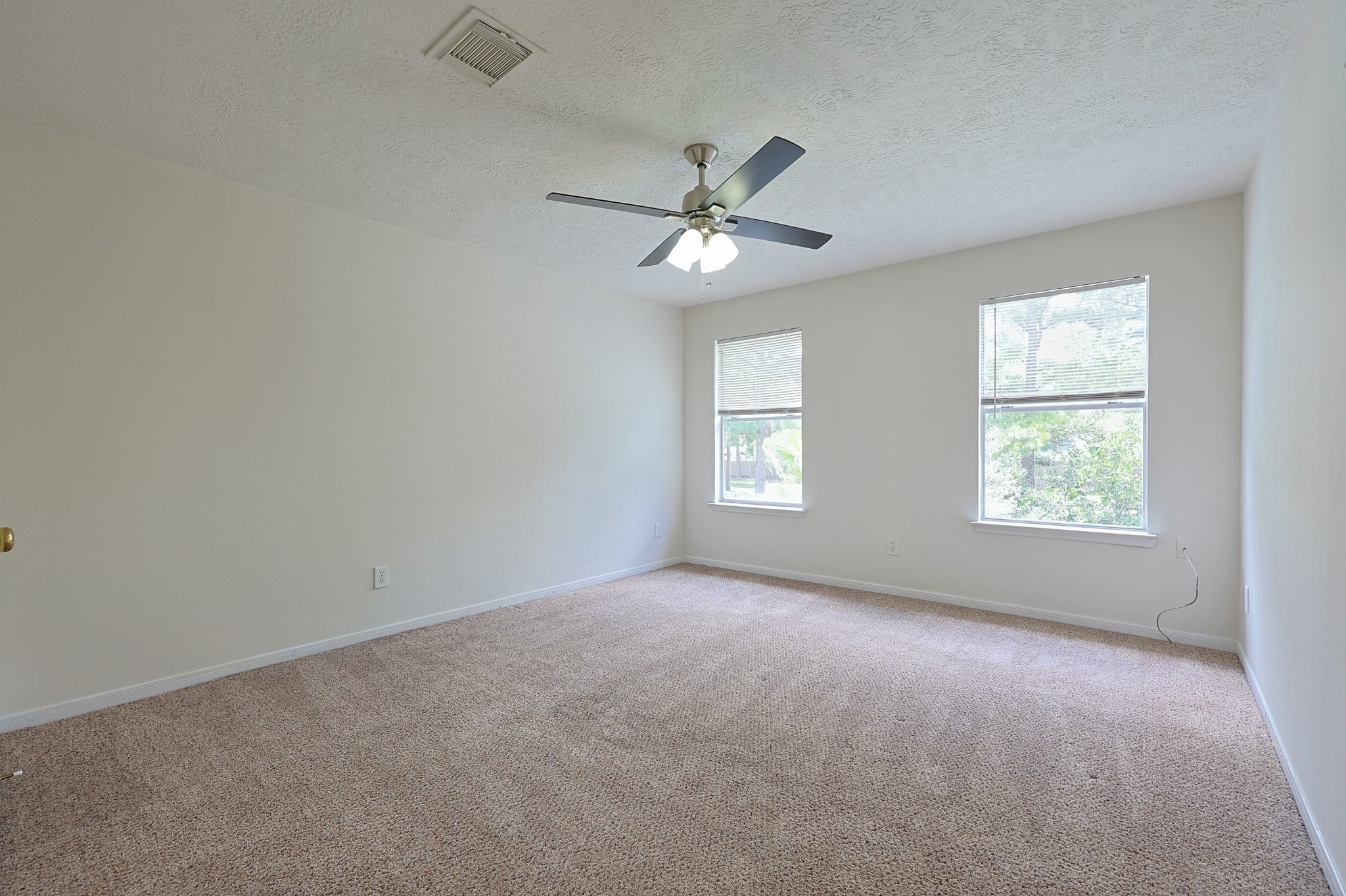 23019 Eastgate Village Drive Spring, TX 77373 - Photo 31 of 46 This spacious bedroom 2 features neutral carpet, a ceiling fan, and two large windows that provide plenty of natural light.