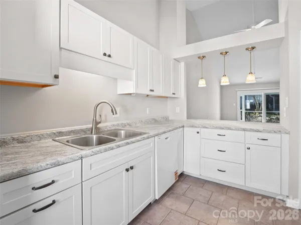 a kitchen with white cabinets and sink