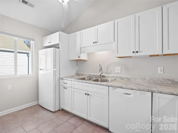 a kitchen with granite countertop white cabinets and white appliances