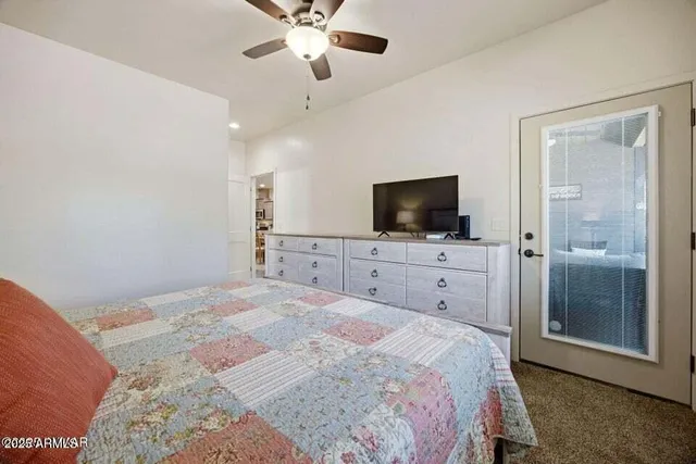 a bedroom with a large bed and a flat tv screen on dresser