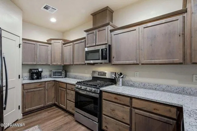 a kitchen with granite countertop a sink cabinets and stainless steel appliances