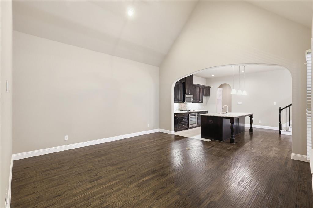 768 Huntingdon Street Coppell, TX 75019 - Photo 4 of 37 Open and airy living space with soaring ceilings, rich hardwood flooring, and a graceful archway connecting the main living area to the kitchen.