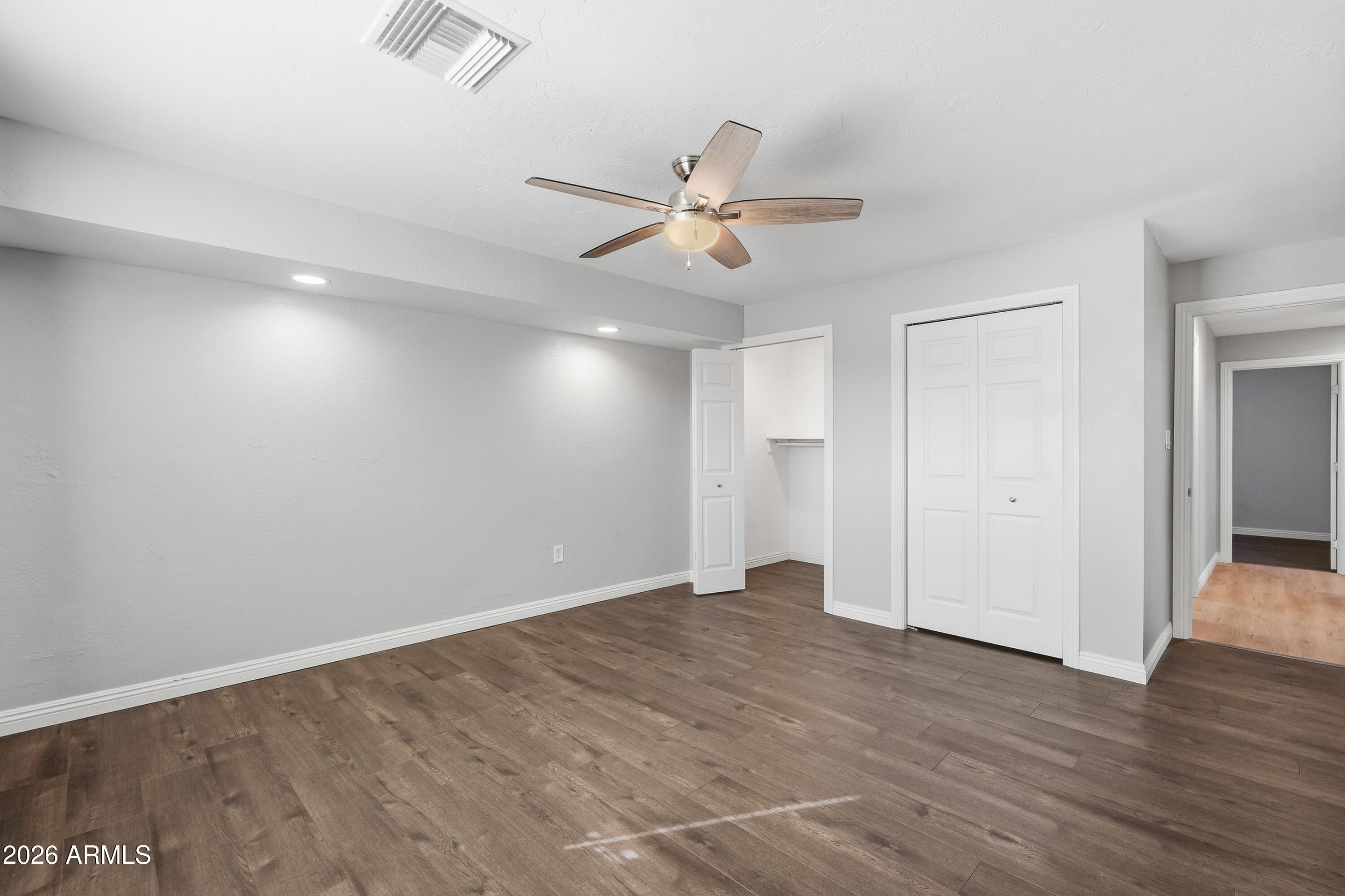 2914 East Cactus Road Phoenix, AZ 85032 - Photo 21 of 40 an empty room with wooden floor ceiling fan and windows