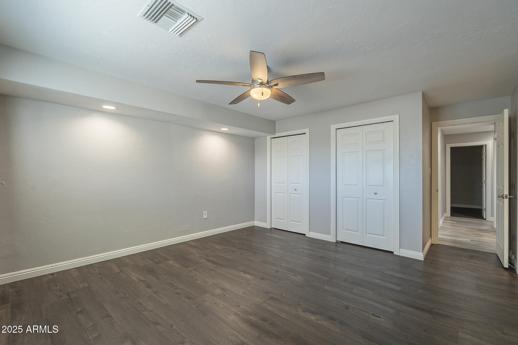 2914 East Cactus Road Phoenix, AZ 85032 - Photo 26 of 49 an empty room with wooden floor chandelier fan and windows