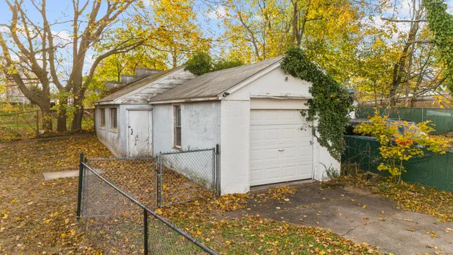 a view of a white house next to a yard with big trees