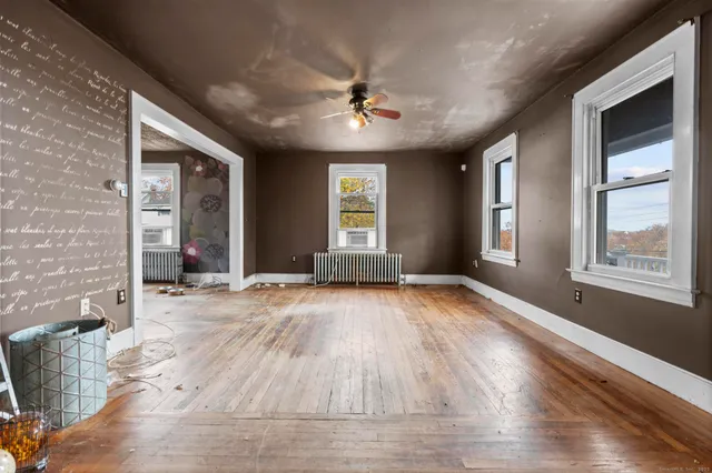 a view of an empty room with wooden floor and a window