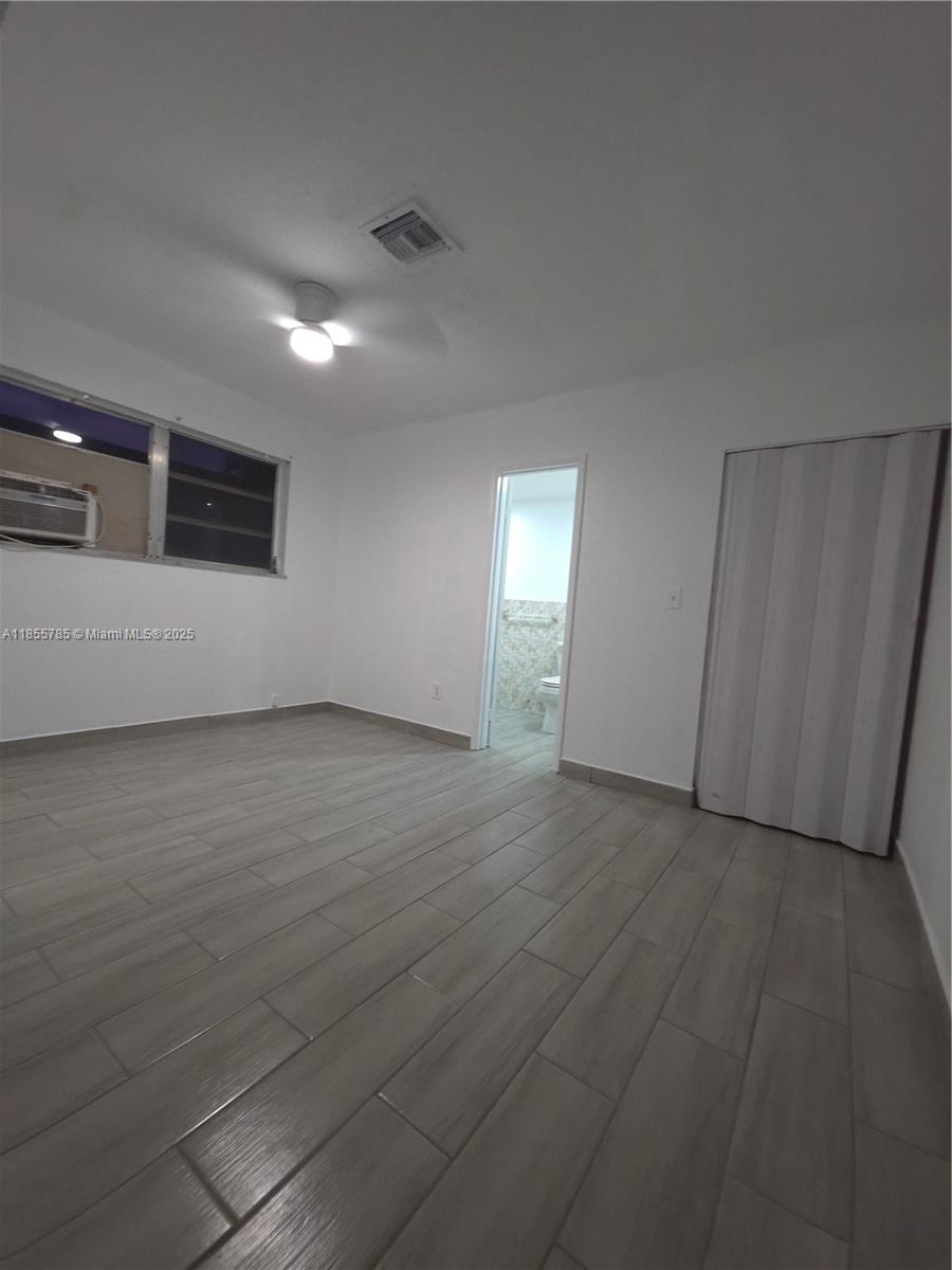 359 West 12th Street, Unit 2 Hialeah, FL 33010 - Photo 17 of 20 an empty room with wooden floor and windows