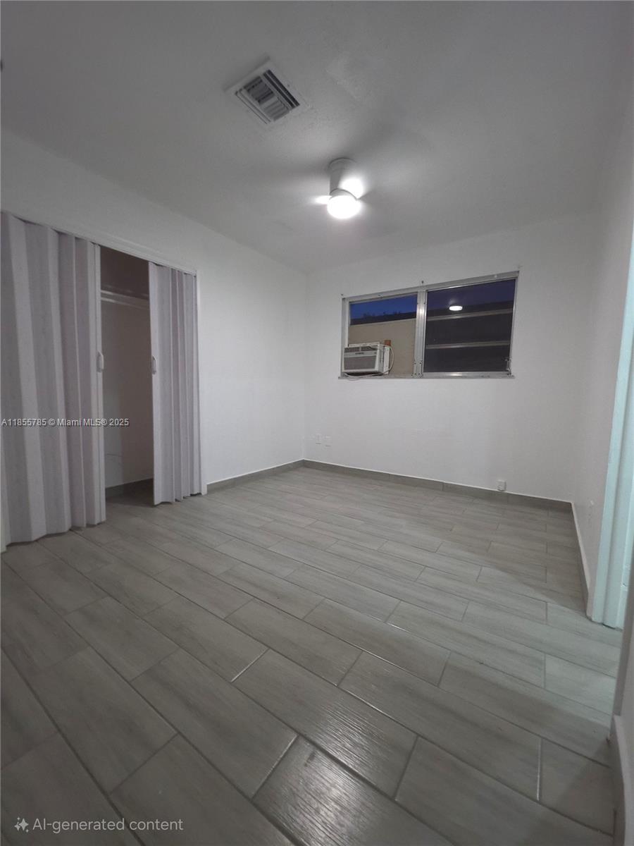 359 West 12th Street, Unit 2 Hialeah, FL 33010 - Photo 18 of 20 an empty room with wooden floor and windows
