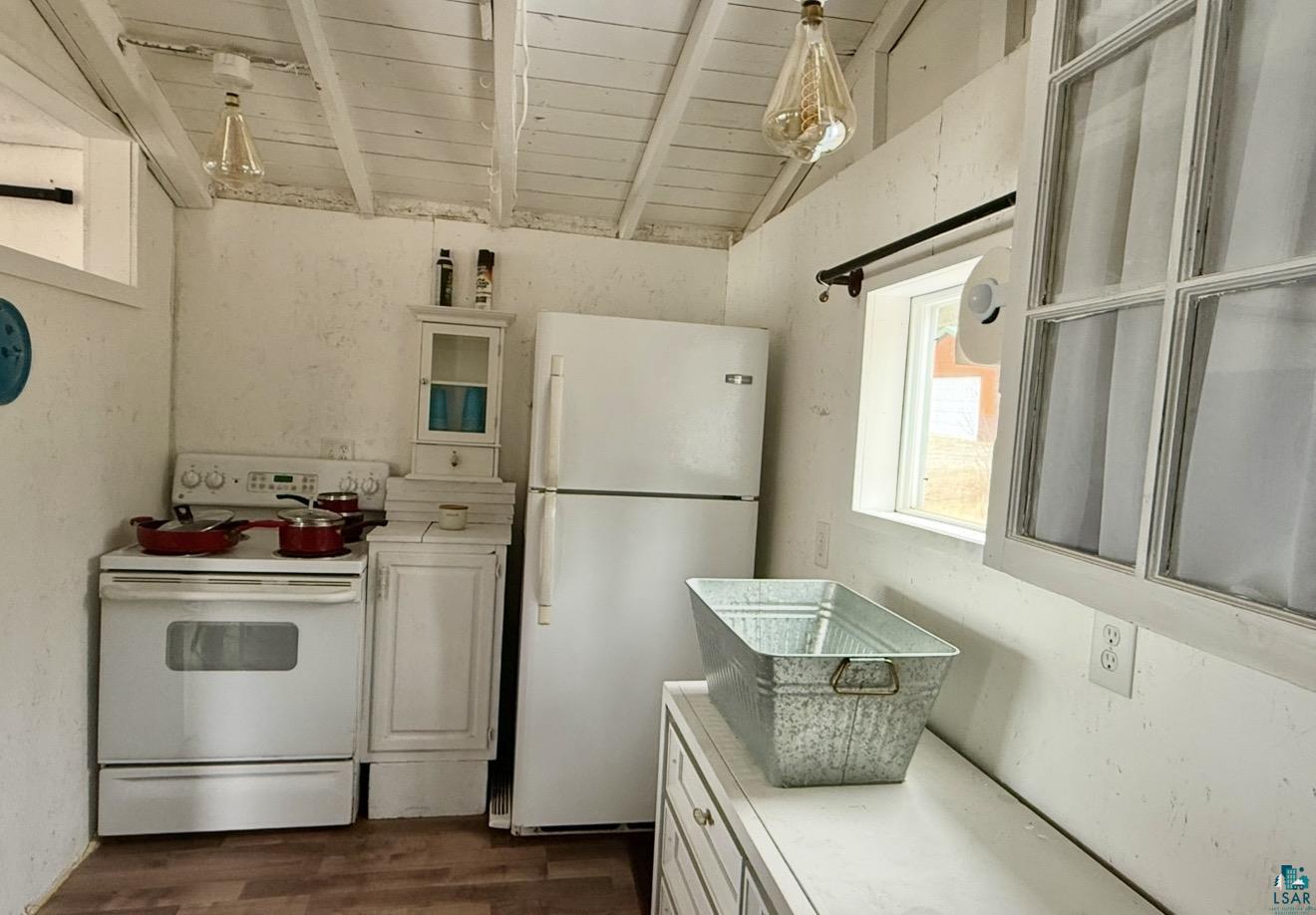 9572 Bonner Road Mountain Iron, MN 55768 - Photo 8 of 20 Kitchen with white cabinets, light countertops, white appliances, dark wood-style floors, and vaulted ceiling with beams