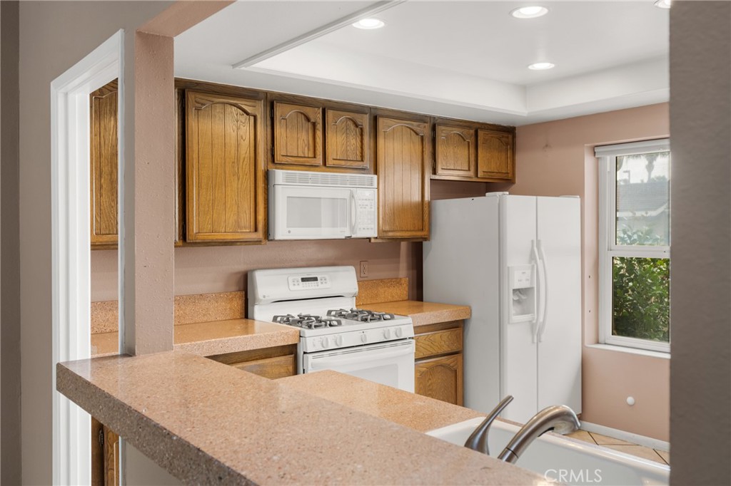10 Greenbriar, Unit 31 Irvine, CA 92604 - Photo 12 of 46 a kitchen with a refrigerator a stove a sink dishwasher and wooden cabinets with wooden floor