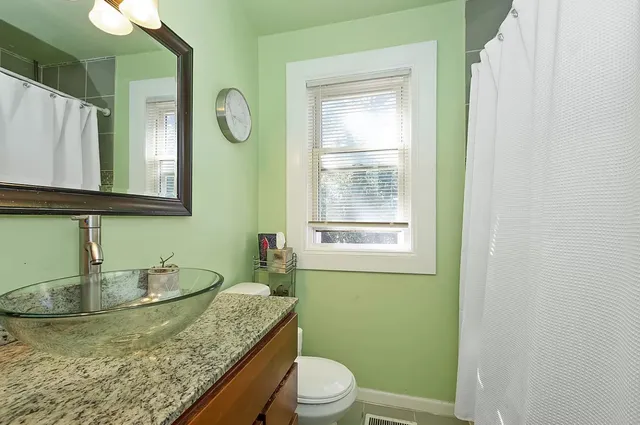 a bathroom with a granite countertop sink a toilet and a mirror