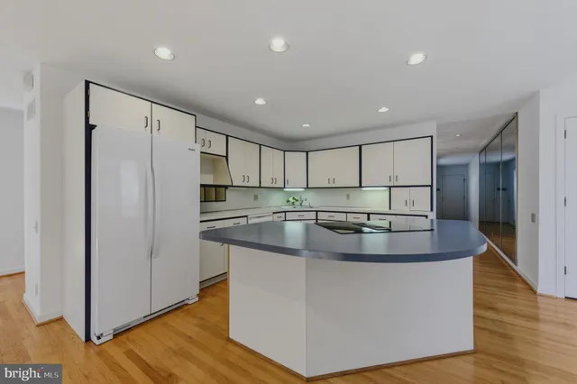 a kitchen with stainless steel appliances granite countertop a refrigerator a sink and a stove with wooden floor