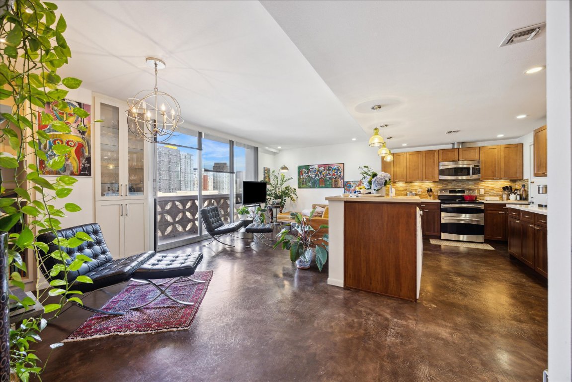 a living room with furniture a chandelier and kitchen view