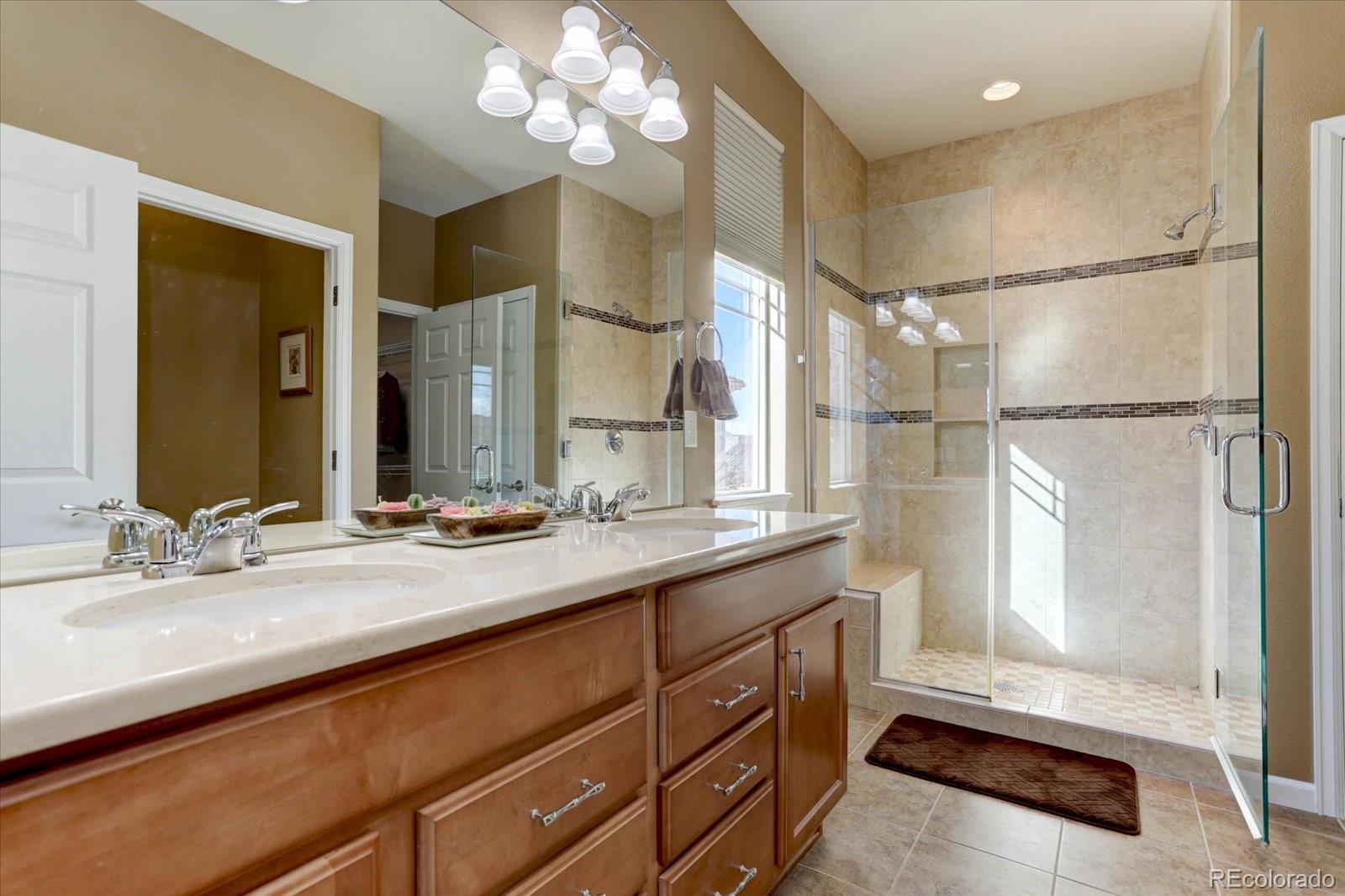 15932 Torreys Way Broomfield, CO 80023 - Photo 16 of 31 a bathroom with a sink a large mirror and a shower
