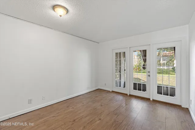an empty room with wooden floor and windows