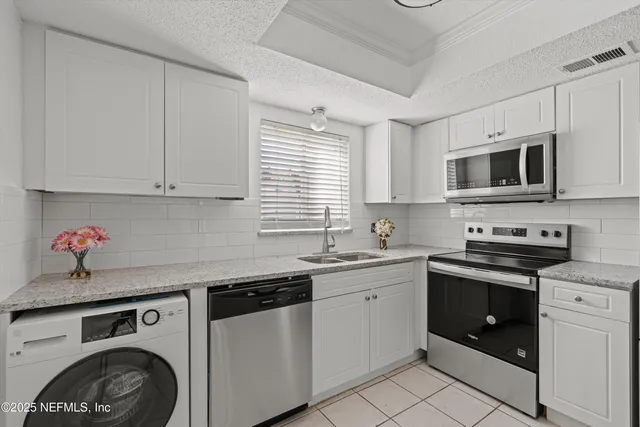 a kitchen with stainless steel appliances granite countertop a sink dishwasher a stove and a microwave oven with cabinets