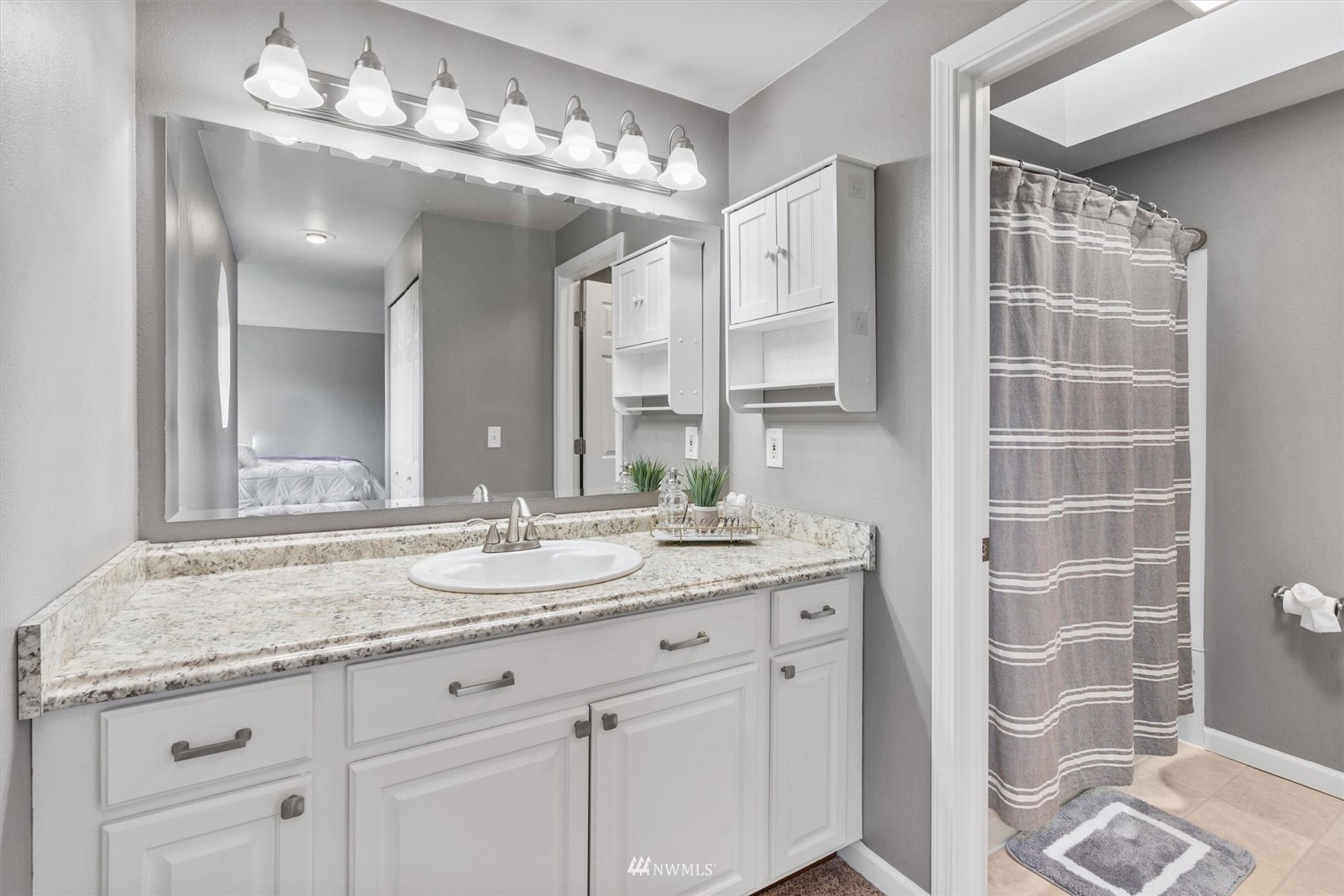 1208 228th Place Southwest Bothell, WA 98021 - Photo 19 of 33 a bathroom with a granite countertop sink a mirror and a shower