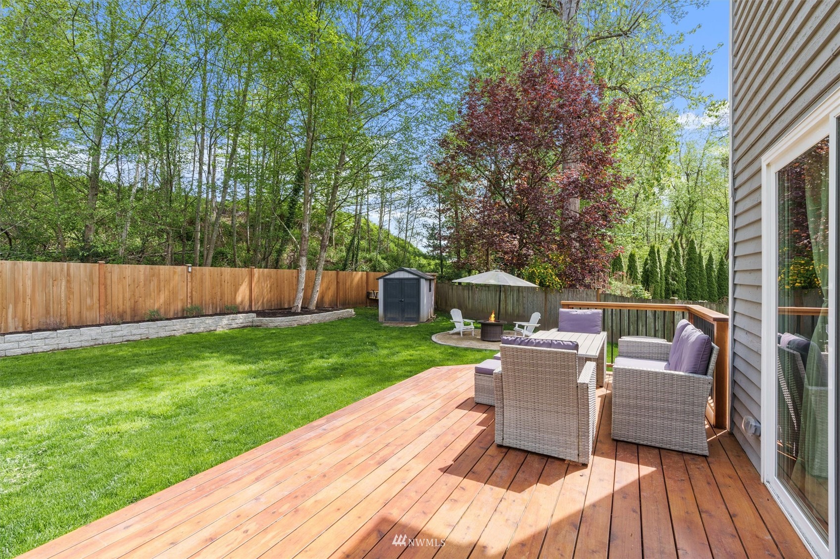 1208 228th Place Southwest Bothell, WA 98021 - Photo 26 of 33 a view of a deck with a table and chairs couches fire pit and wooden fence