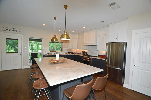 a kitchen with stainless steel appliances granite countertop a refrigerator a stove a sink dishwasher a dining table and chairs with wooden floor