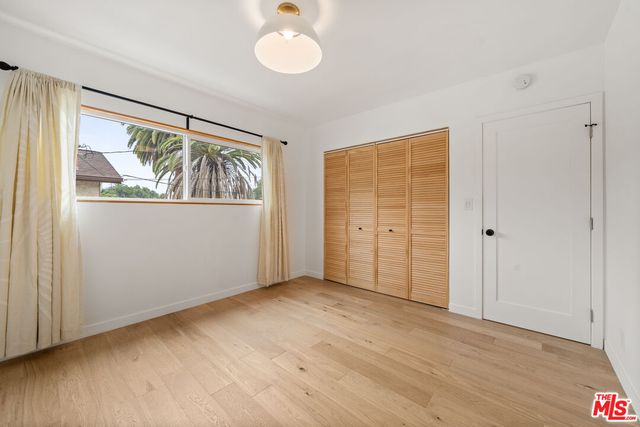 an empty room with wooden floor closet and windows