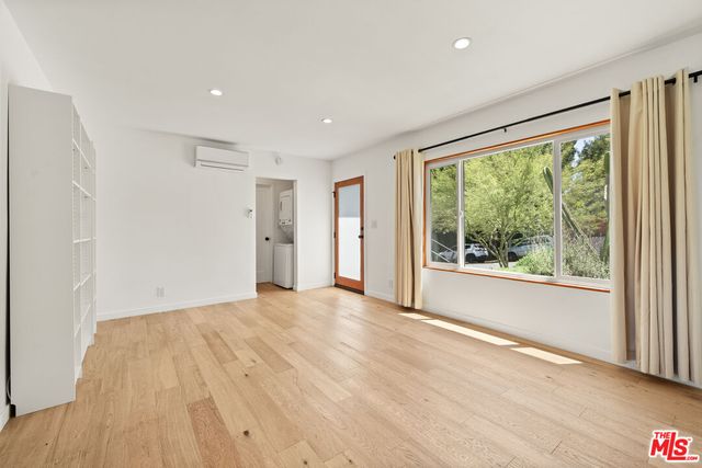a view of an empty room with a window and a kitchen