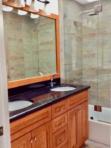 a bathroom with a granite countertop sink a toilet and shower