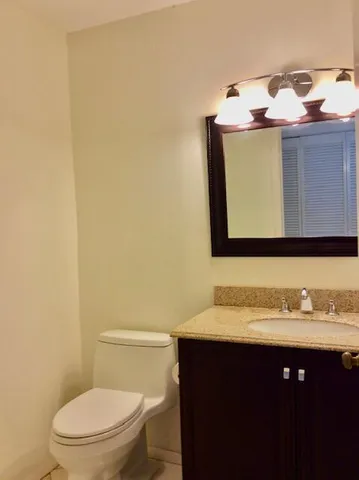 a bathroom with a sink vanity mirror and toilet