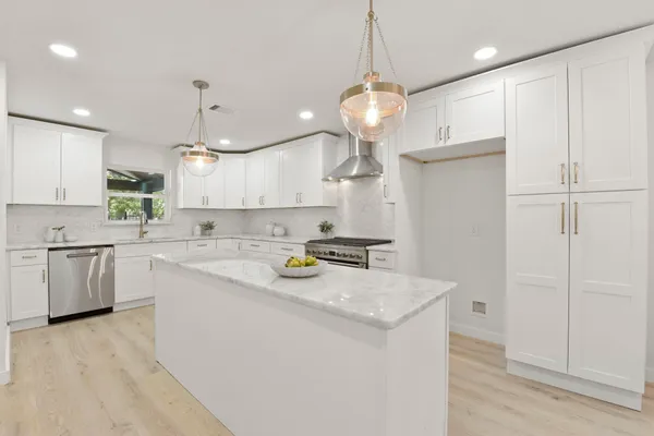 a kitchen with stainless steel appliances granite countertop a sink a stove and a refrigerator