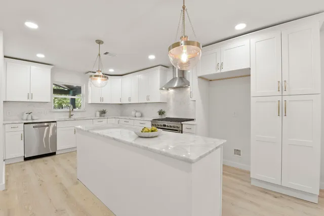 a kitchen with stainless steel appliances granite countertop a sink a stove and a refrigerator