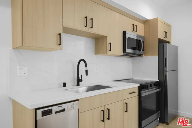 a kitchen with white cabinets a sink and stainless steel appliances