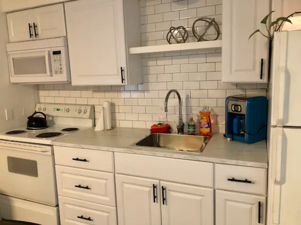 5909 Bolm Road, Unit 12 Austin, TX 78721 - Photo 4 of 15 Kitchen with white appliances, light countertops, tasteful backsplash, and white cabinets