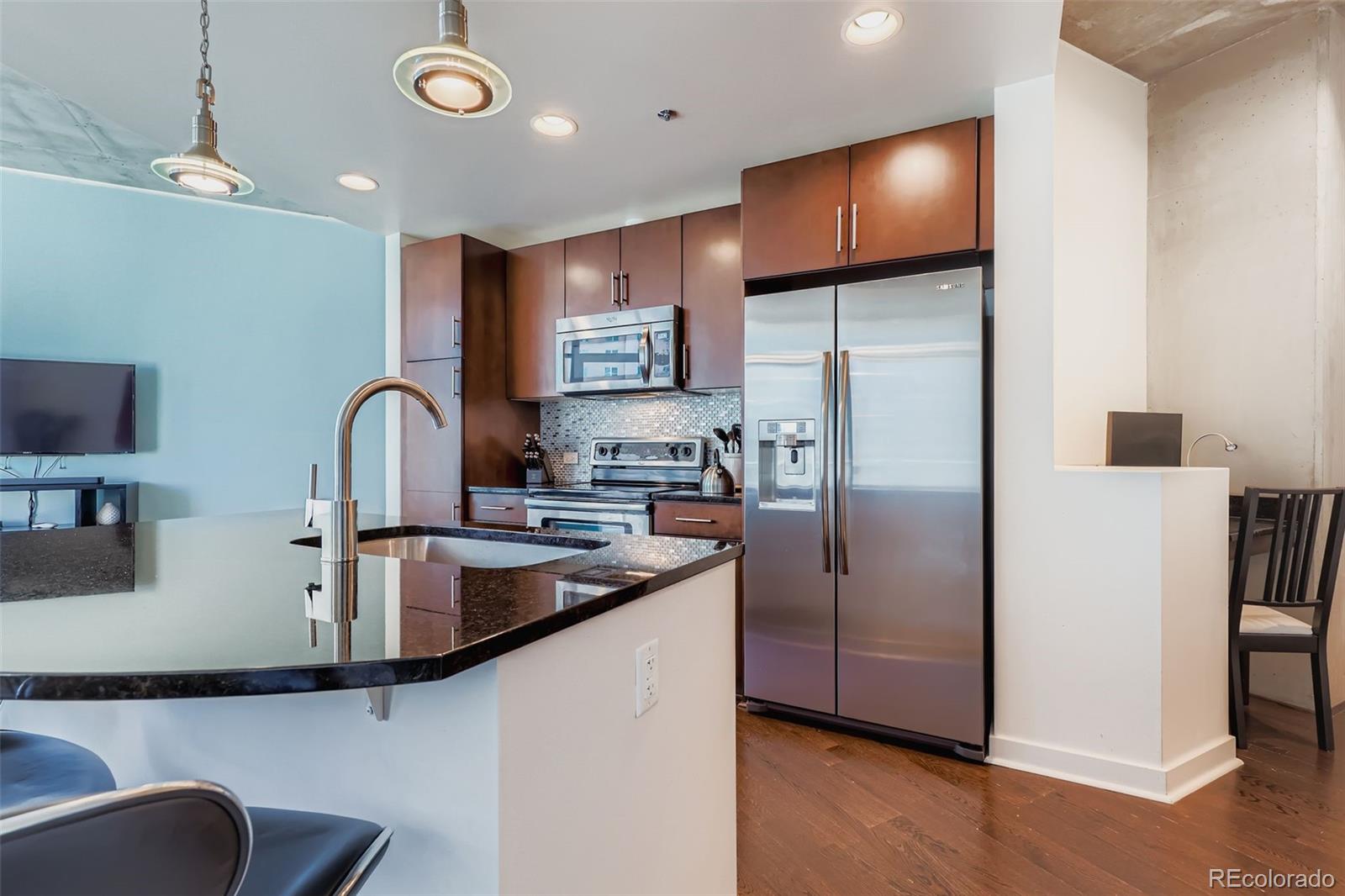 891 14th Street, Unit 1111L Denver, CO 80202 - Photo 4 of 39 a kitchen with stainless steel appliances granite countertop a refrigerator a sink a stove a microwave and island