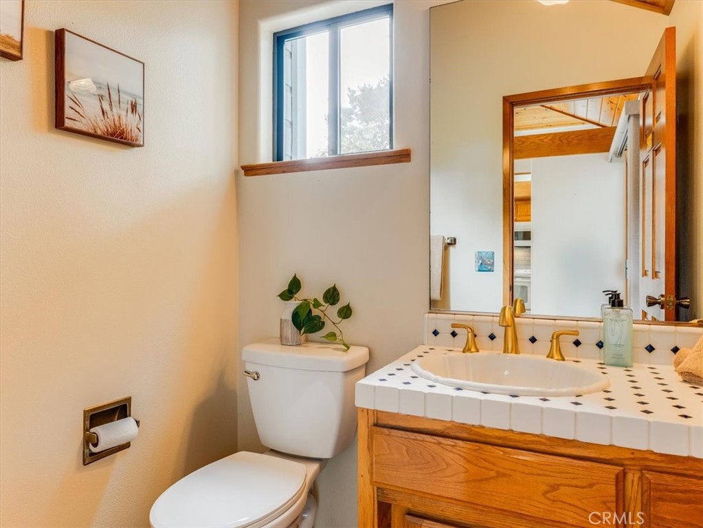 1810 Melrose Avenue Cambria, CA 93428 - Photo 17 of 74 a bathroom with a granite countertop toilet sink and mirror