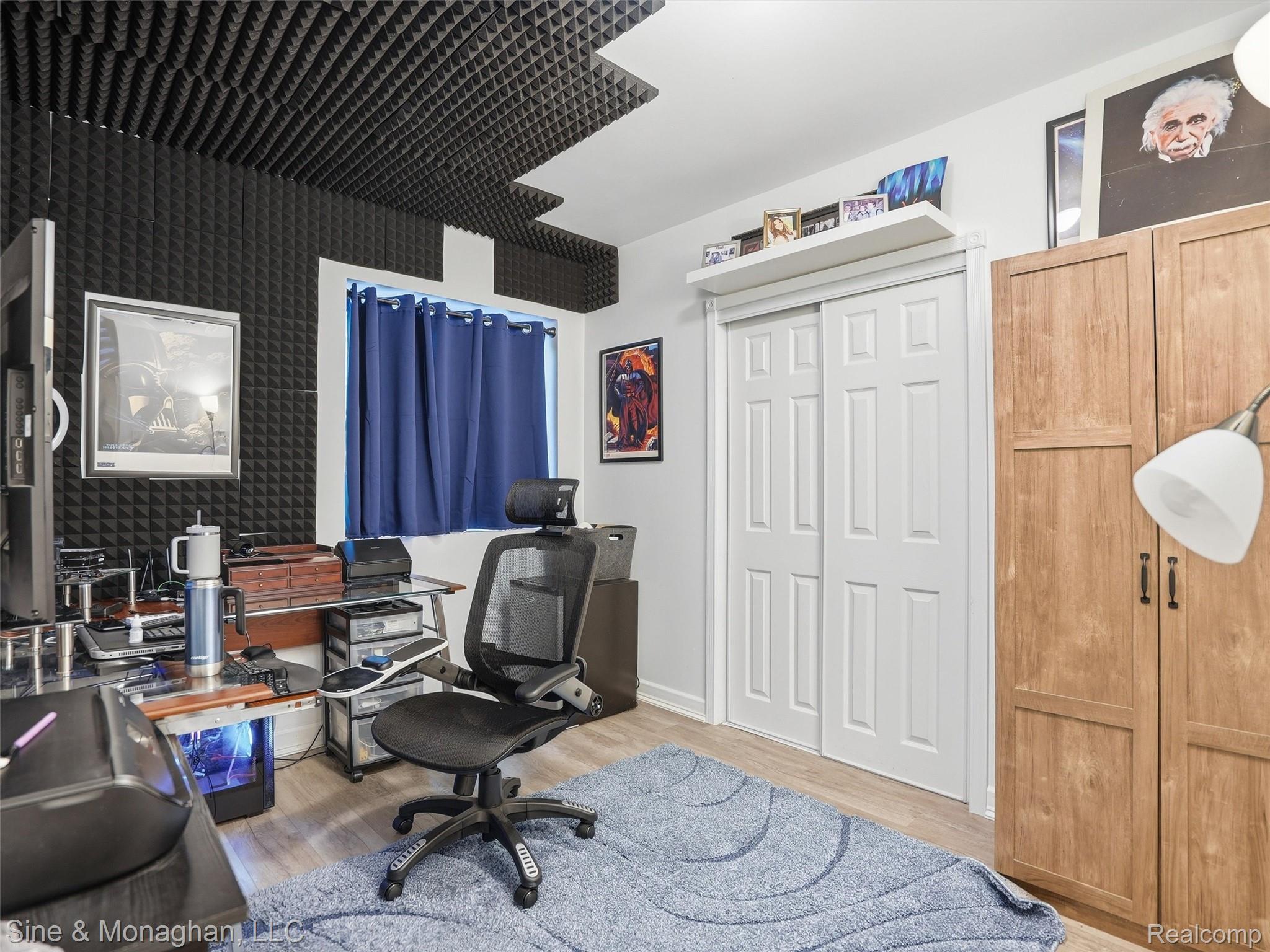 24827 Ivy Road Novi, MI 48375 - Photo 32 of 38 Room featuring acoustic paneling on walls and ceiling, wood-finish flooring, and a window with blue curtains