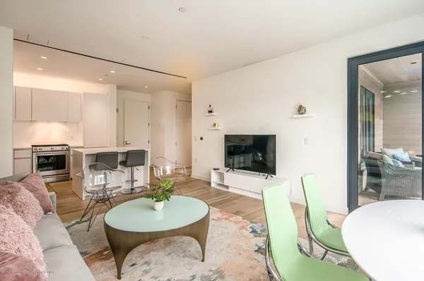 a living room with furniture a flat screen tv and kitchen view