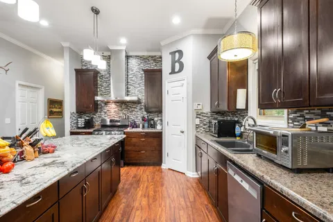 a kitchen with stainless steel appliances granite countertop stove a sink dishwasher and wooden cabinets with wooden floor