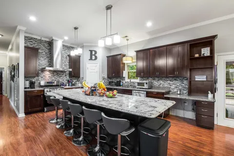 a kitchen with granite countertop a table chairs stainless steel appliances and wooden floor