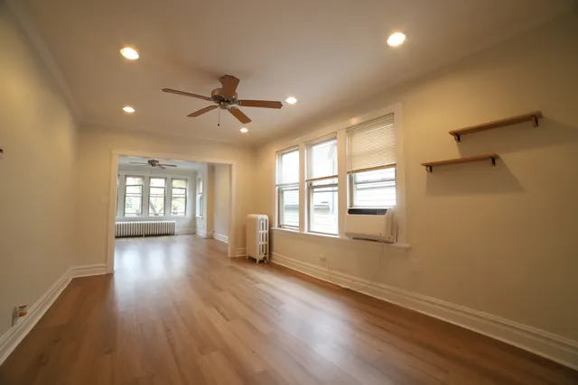 a view of an empty room with a window and wooden floor