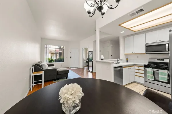 a kitchen with stainless steel appliances granite countertop a stove top oven a sink dishwasher a dining table and chairs with wooden floor