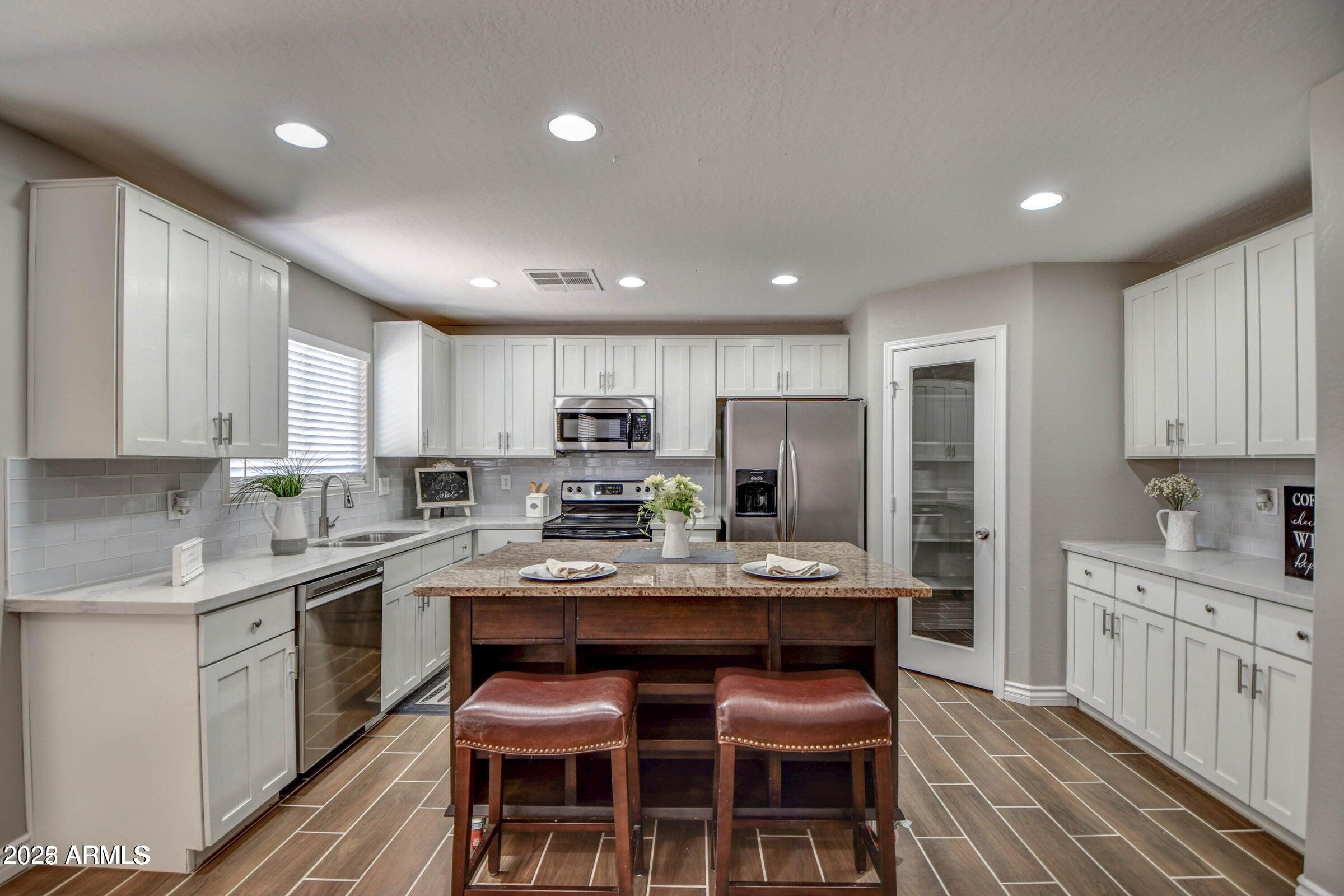 45338 West Norris Road Maricopa, AZ 85139 - Photo 4 of 6 a large kitchen with kitchen island granite countertop a sink and cabinets