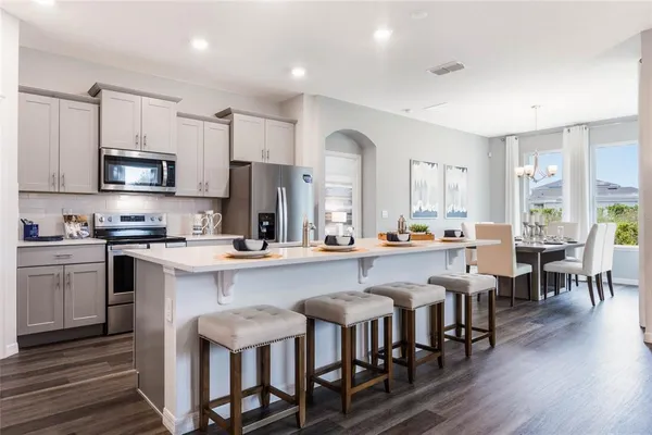 a kitchen with stainless steel appliances a dining table chairs microwave and cabinets