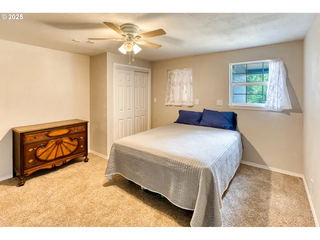 a bedroom with a bed a dresser with wooden floor